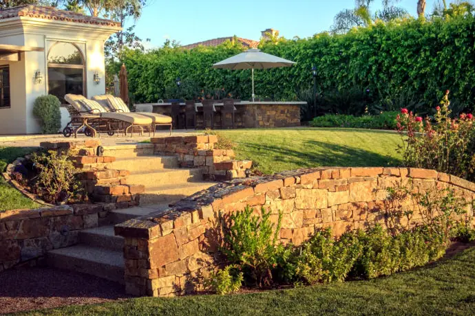 Dry-stacked natural sandstone retaining wall with concrete steps cut through it
