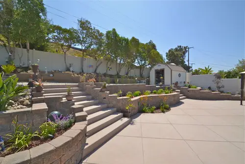 Broom-finished concrete patio with block retaining walls and steps