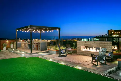 Steel-frame pergola over a bar and grill area beside a linear gas fireplace