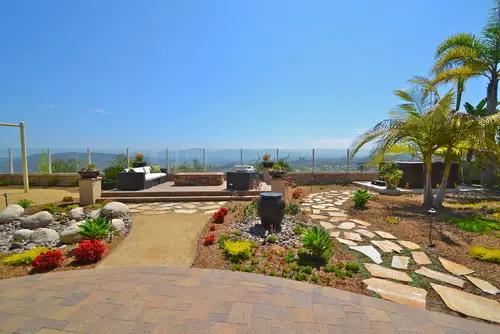 Irregular flagstone stepping path set in gravel beside a paver patio